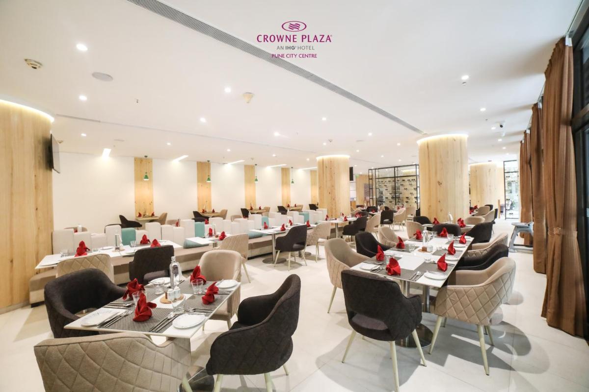 a restaurant with tables and chairs in a room at Crowne Plaza Pune City Centre by IHG in Pune
