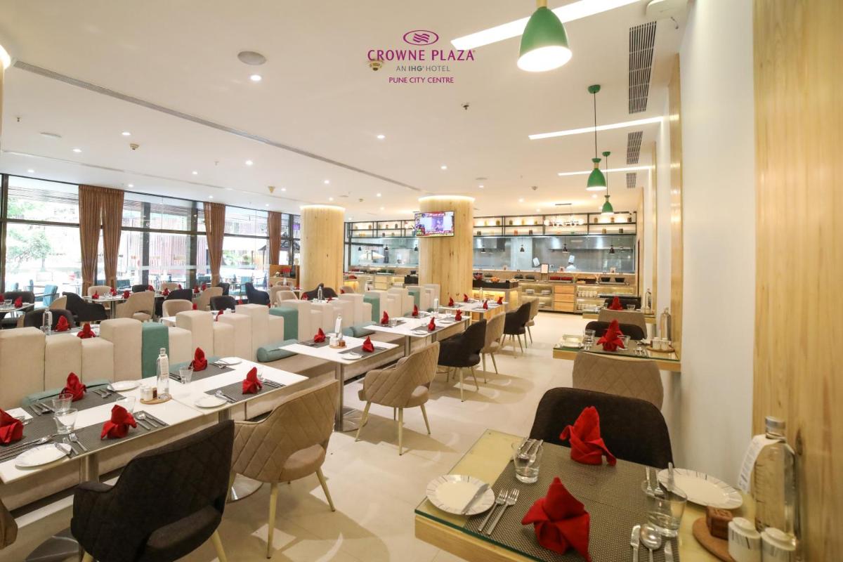 a restaurant with tables and chairs with red bows at Crowne Plaza Pune City Centre by IHG in Pune