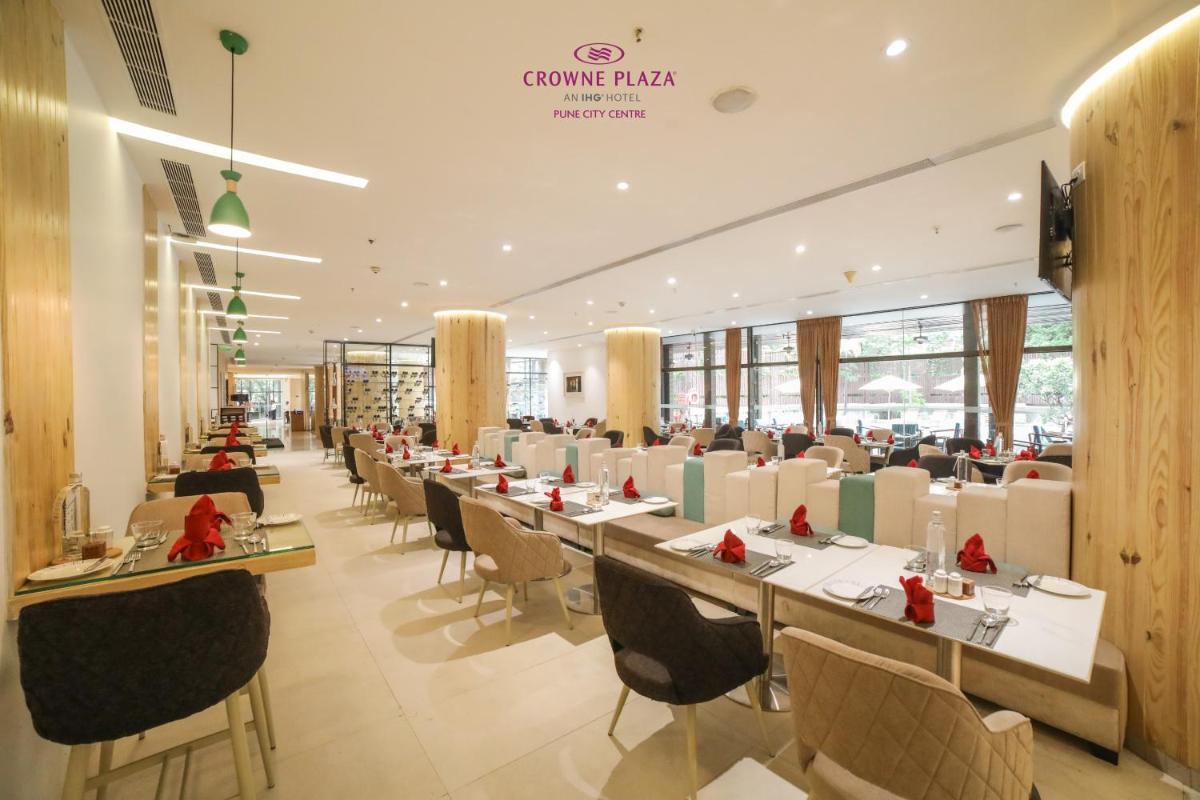 a dining room with long tables and chairs at Crowne Plaza Pune City Centre by IHG in Pune