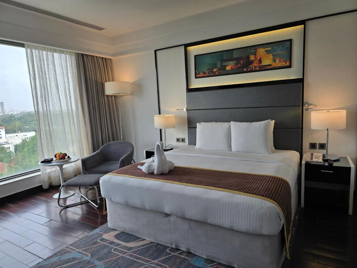 a hotel room with a large bed and a chair at Crowne Plaza Pune City Centre by IHG in Pune
