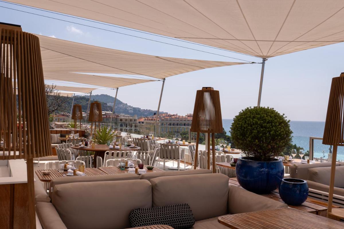 un patio avec des tables, des chaises et un canapé dans l'établissement Maison Albar - Le Victoria, à Nice