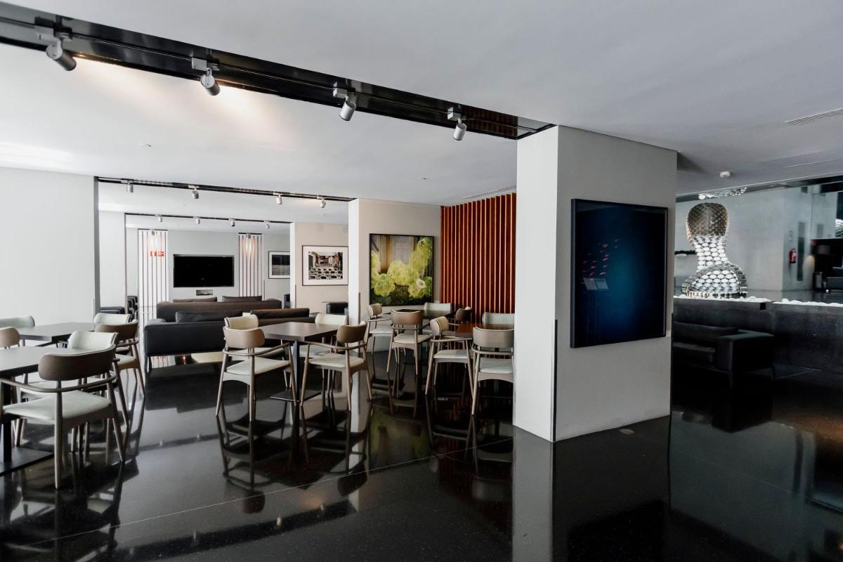 uma sala de estar com mesas e cadeiras e um sofá em Troia Design Hotel em Tróia