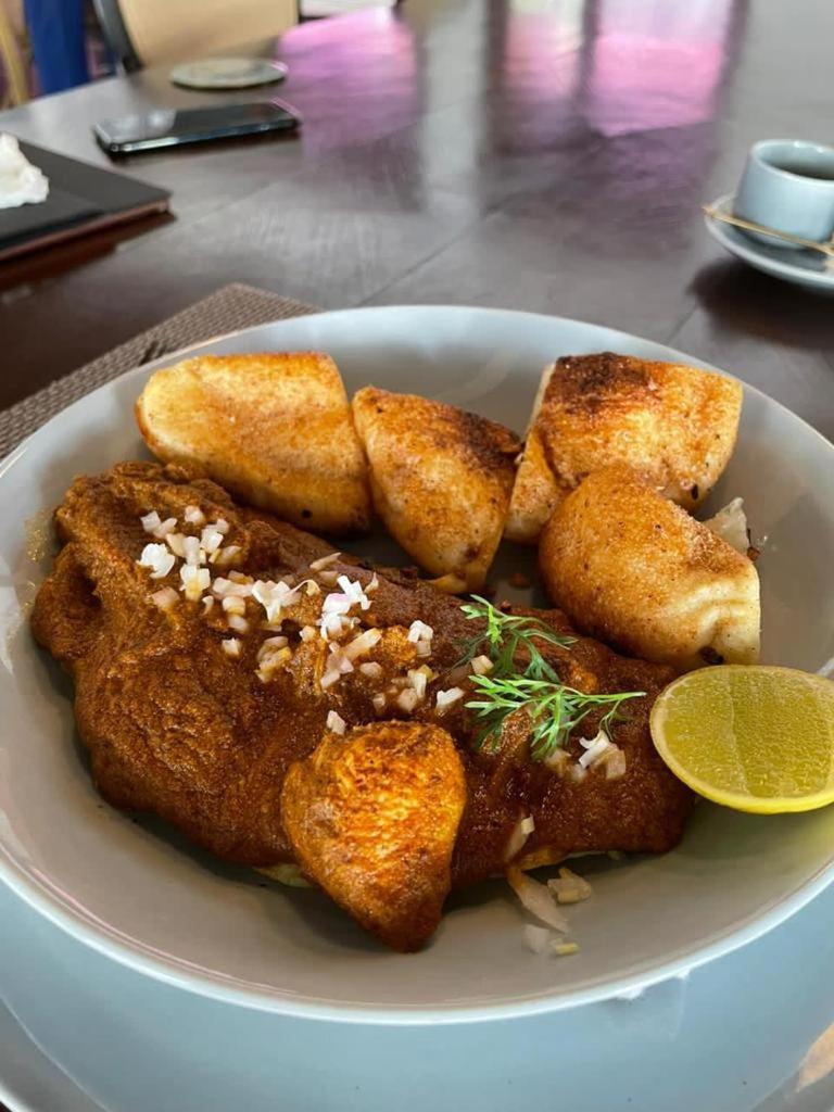 a white plate of food with meat and a slice of lime at The Postcard Saligao in Calangute