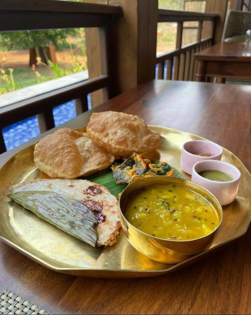 a plate of food with bread and a bowl of soup at The Postcard Saligao in Calangute