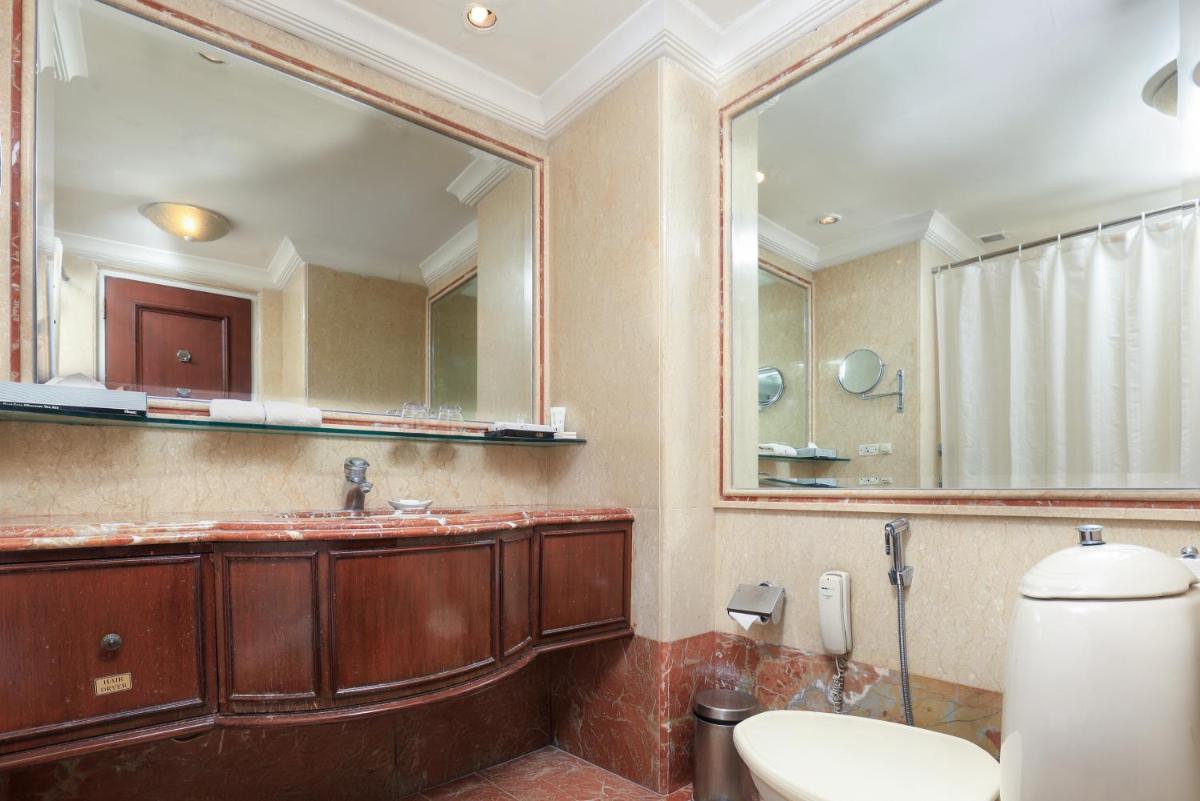 a bathroom with a toilet and a large mirror at Le Royal Meridien Chennai in Chennai