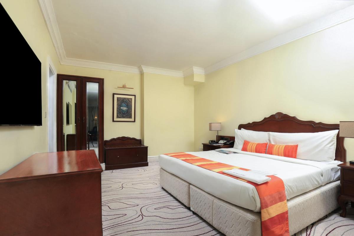 a hotel room with a large bed and a desk at Le Royal Meridien Chennai in Chennai