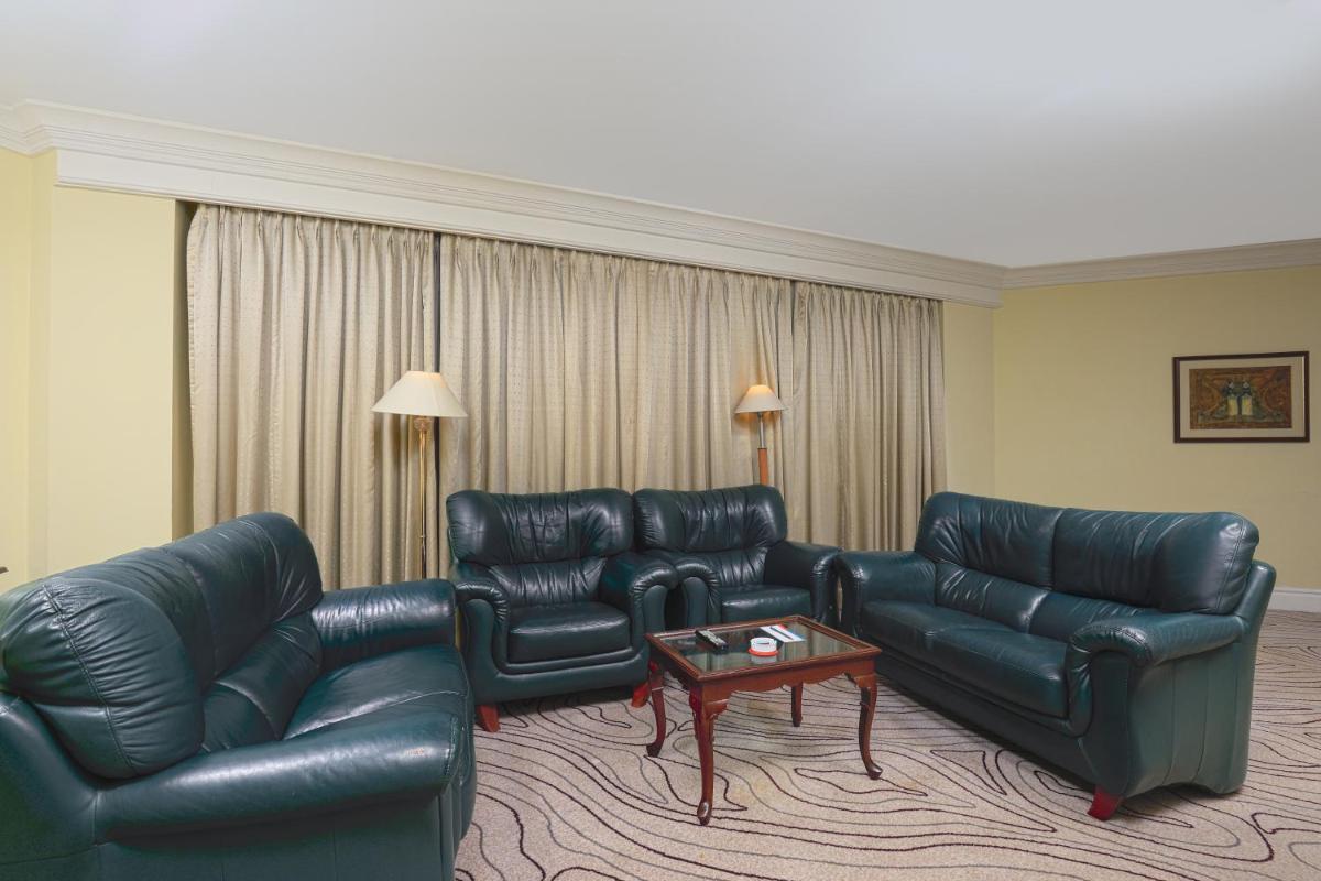 a living room with black leather furniture and a table at Le Royal Meridien Chennai in Chennai