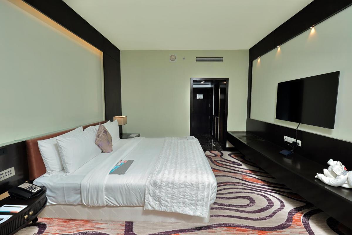 a bedroom with a large bed and a flat screen tv at Le Royal Meridien Chennai in Chennai
