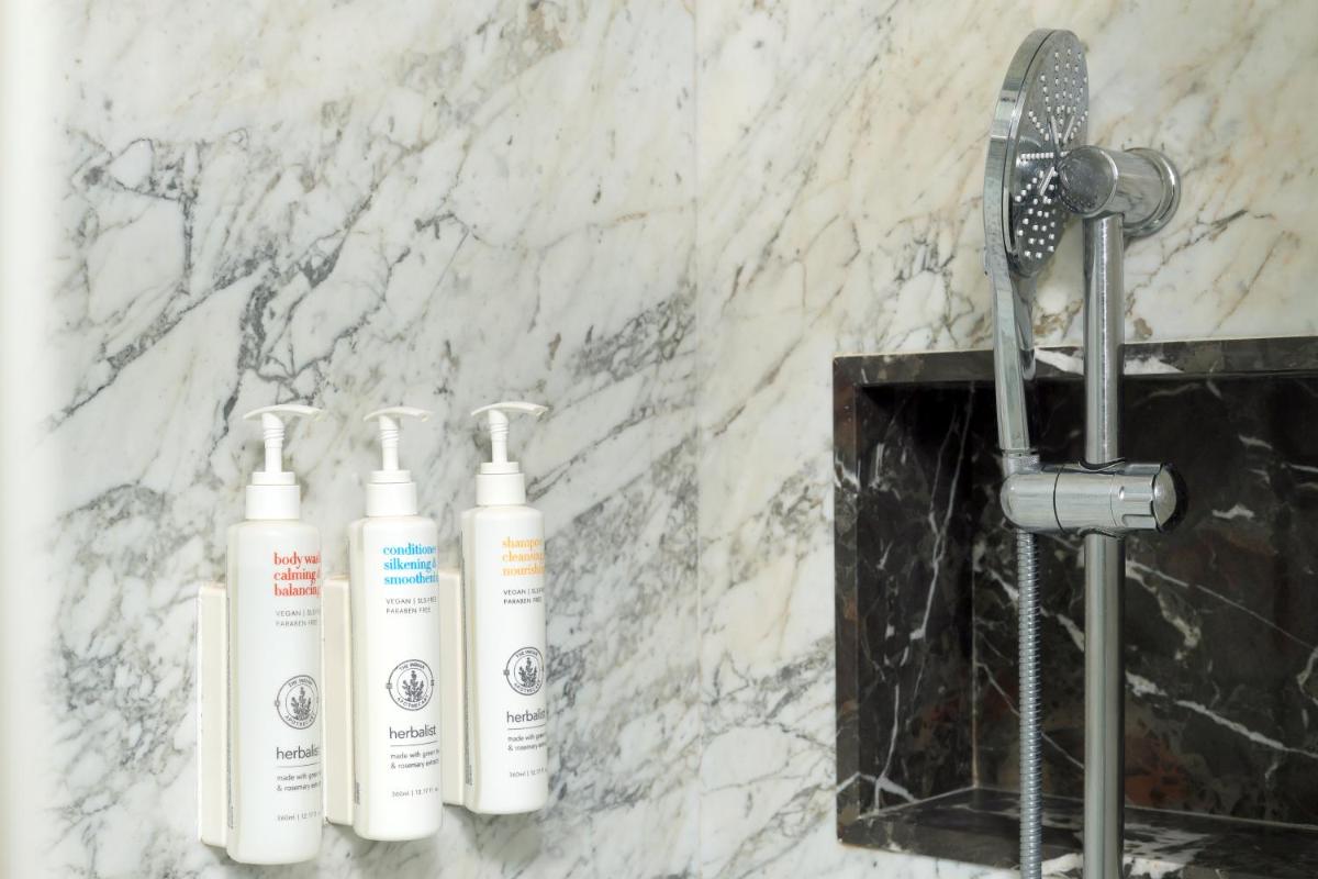 three white shampoo bottles on a counter in a bathroom at Le Royal Meridien Chennai in Chennai