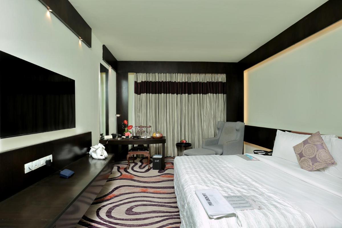 a hotel room with a large bed and a chair at Le Royal Meridien Chennai in Chennai