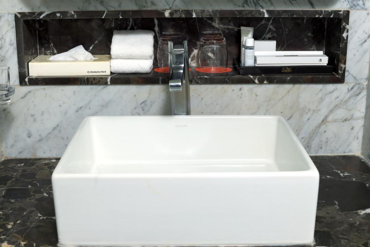a white sink in a bathroom with towels on a shelf at Le Royal Meridien Chennai in Chennai