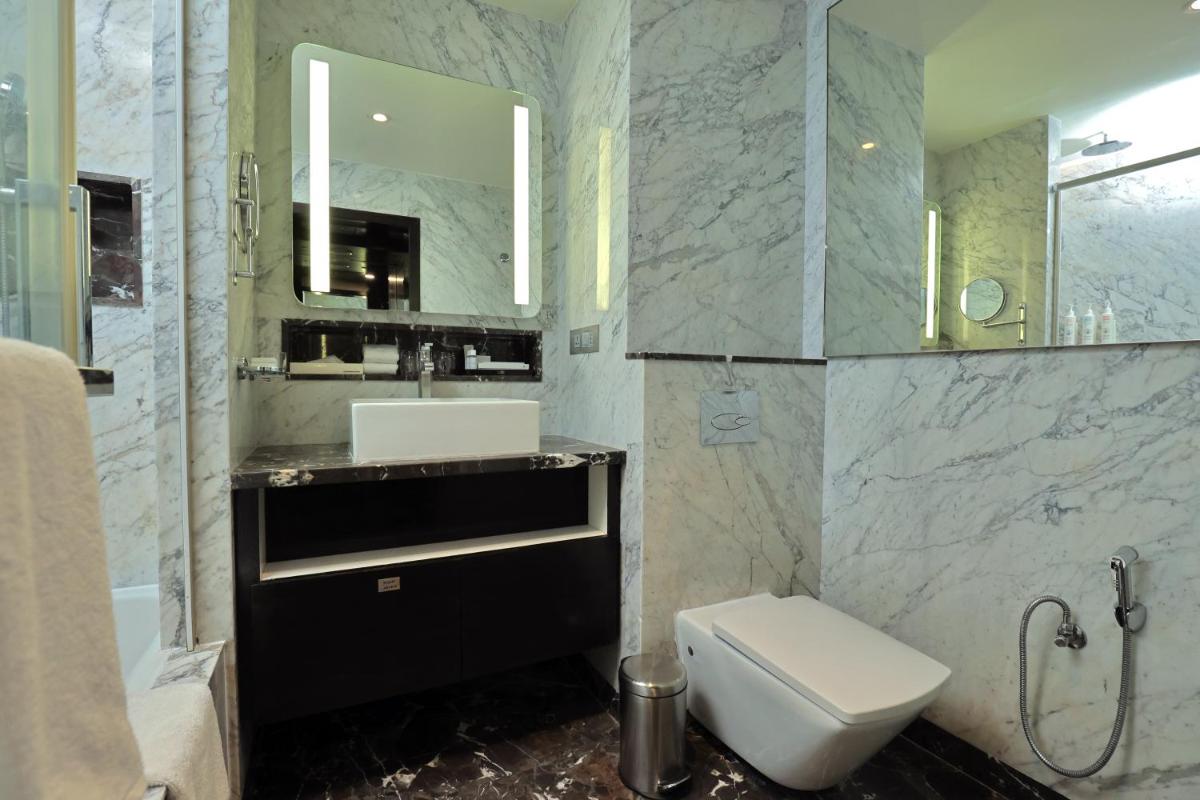 a bathroom with a toilet and a sink and a mirror at Le Royal Meridien Chennai in Chennai
