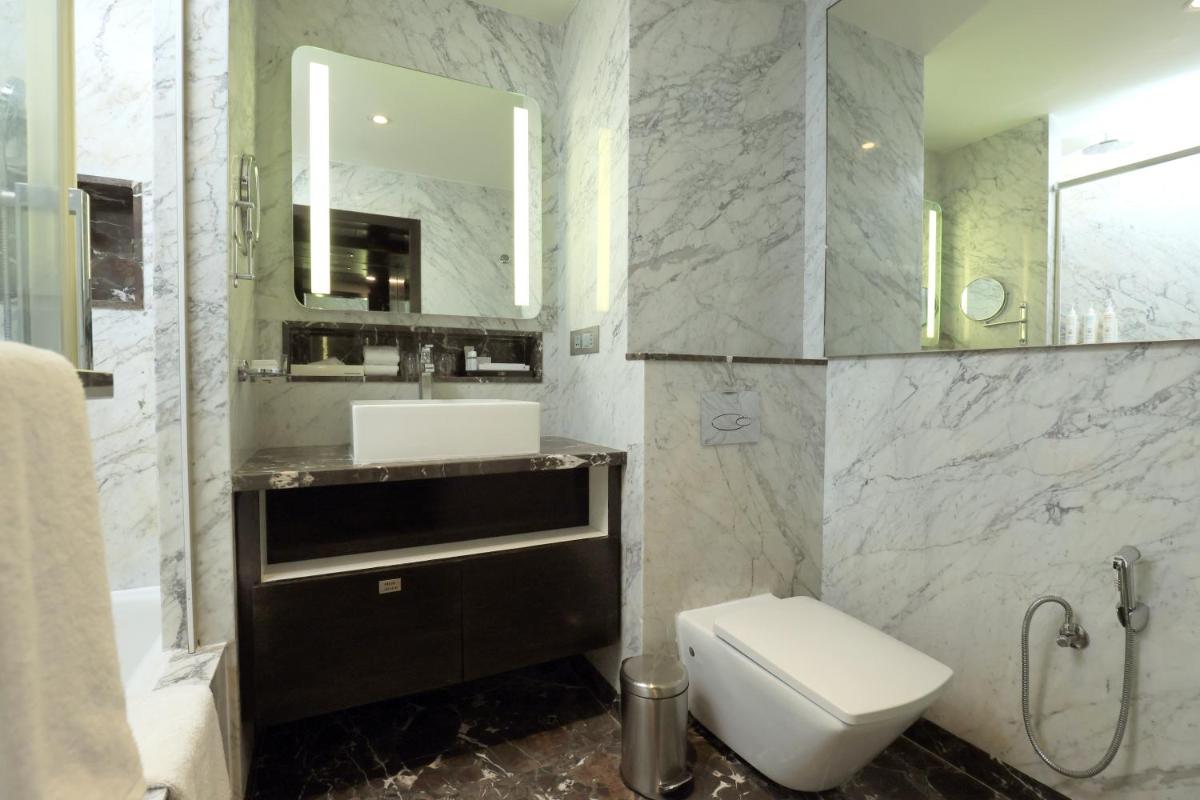 a bathroom with a toilet and a sink and a mirror at Le Royal Meridien Chennai in Chennai