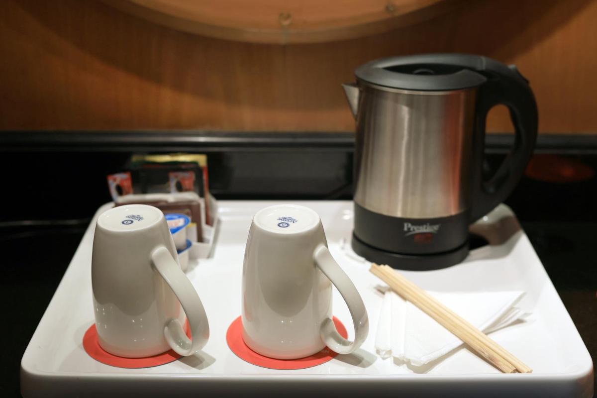 a table with two cups and a coffee pot and chopsticks at Le Royal Meridien Chennai in Chennai