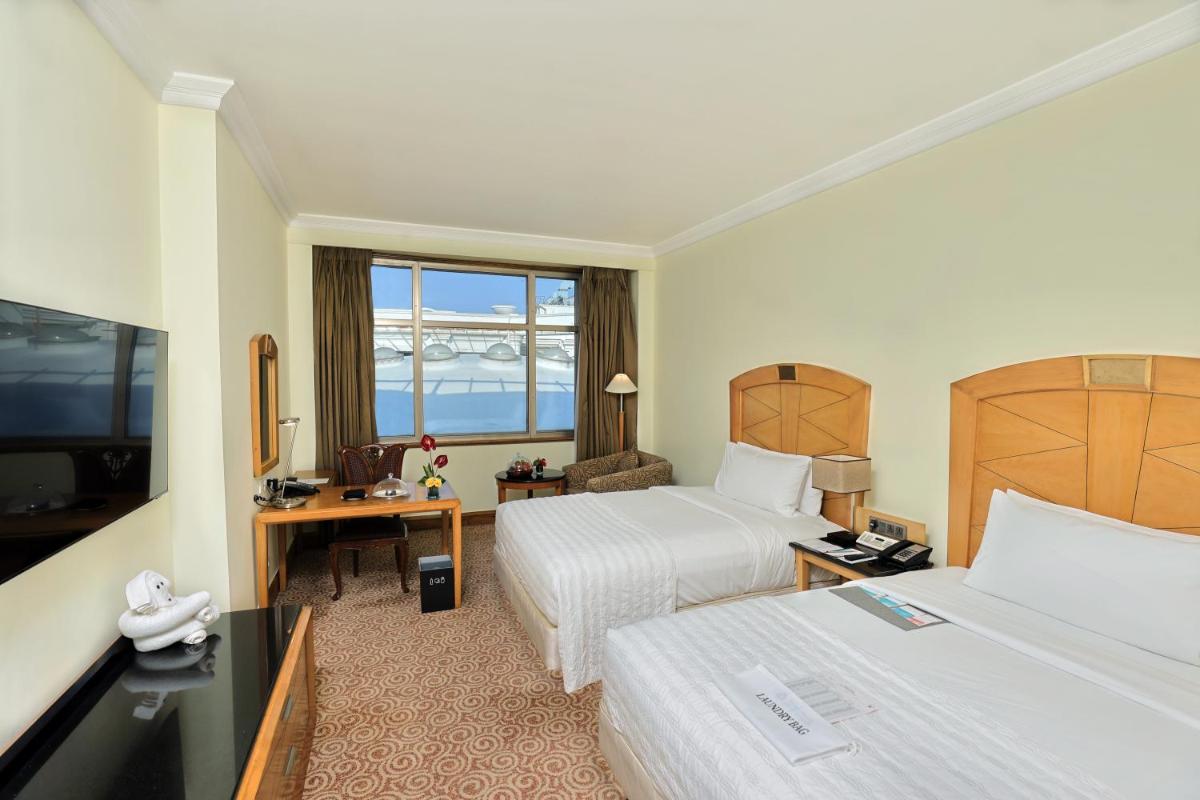 a hotel room with two beds and a television at Le Royal Meridien Chennai in Chennai