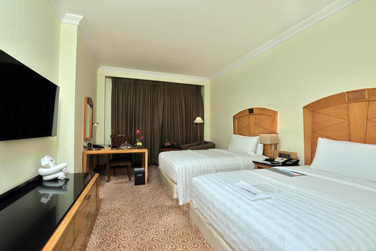 a hotel room with two beds and a flat screen tv at Le Royal Meridien Chennai in Chennai