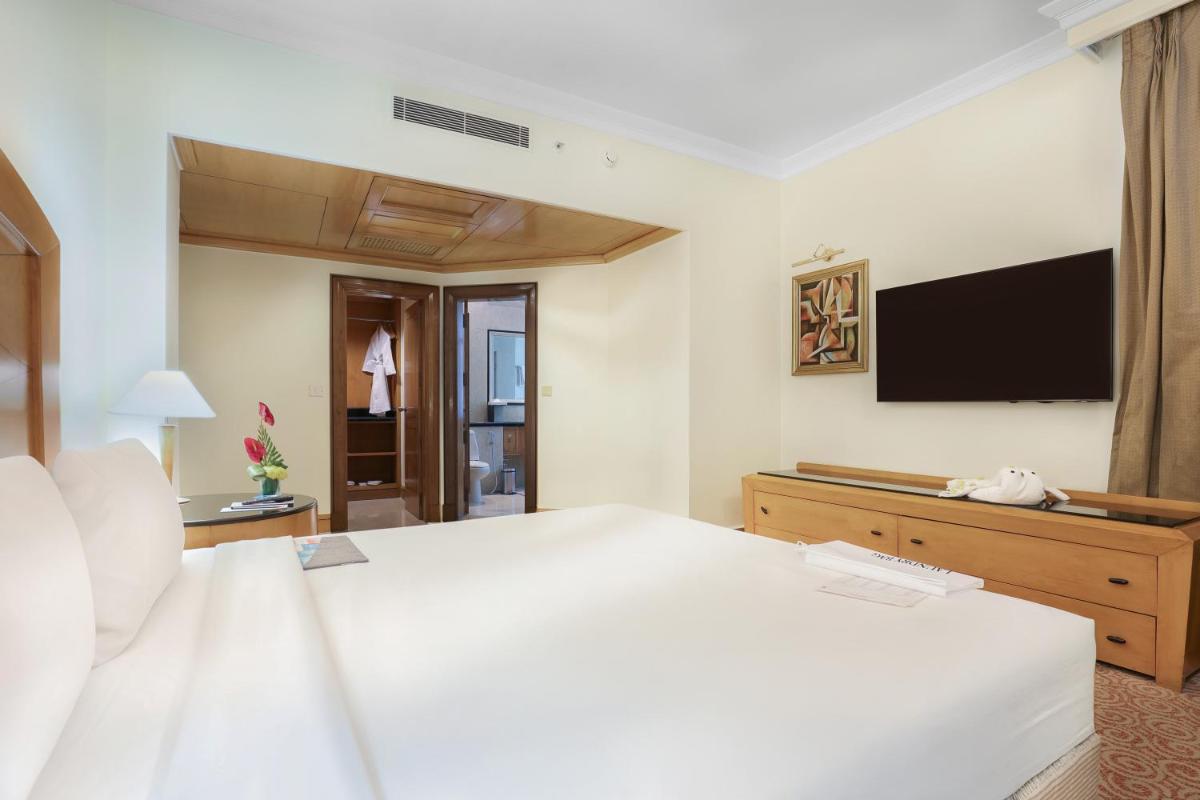 a bedroom with a white bed and a flat screen tv at Le Royal Meridien Chennai in Chennai