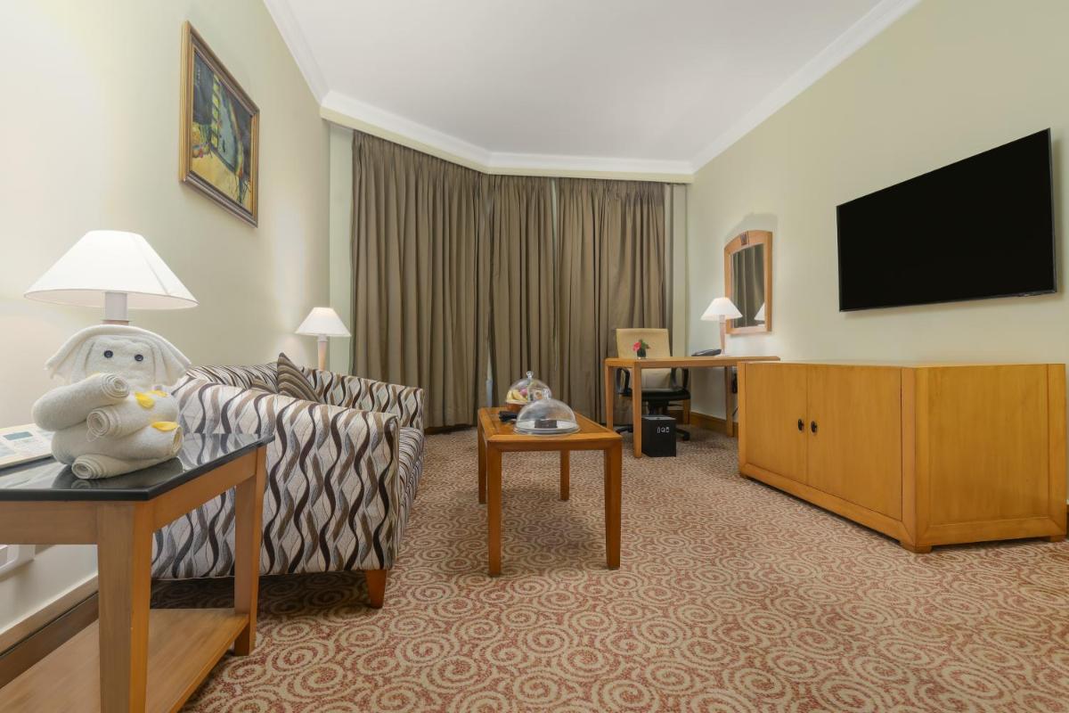 a living room with a couch and a flat screen tv at Le Royal Meridien Chennai in Chennai