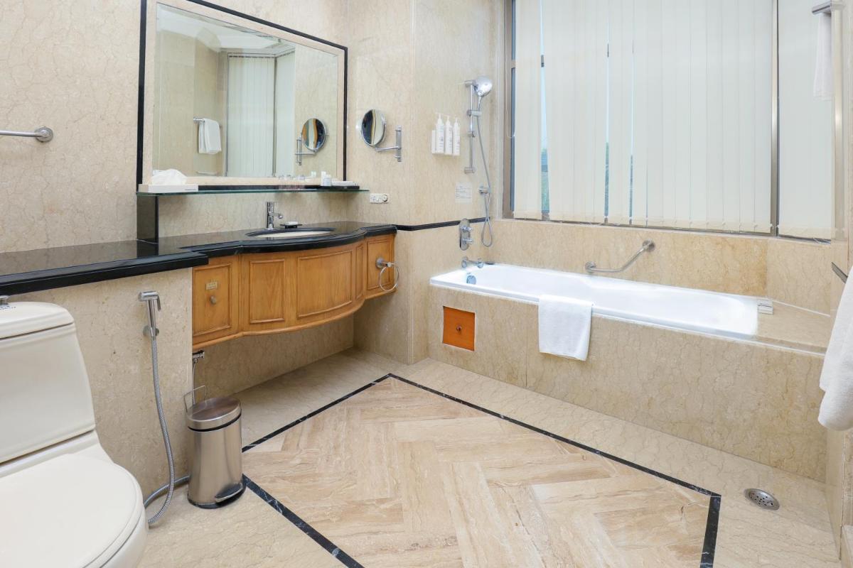 a bathroom with a tub and a sink and a toilet at Le Royal Meridien Chennai in Chennai