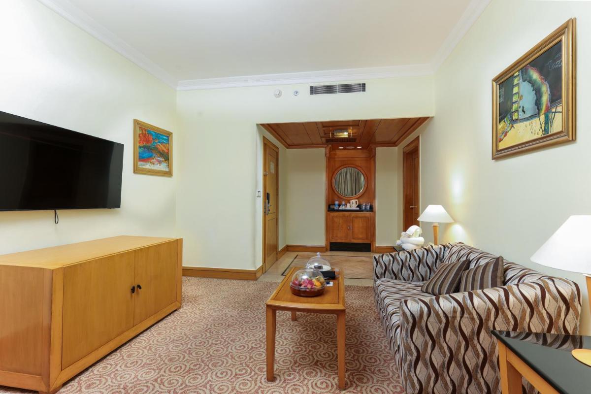 a living room with a couch and a flat screen tv at Le Royal Meridien Chennai in Chennai