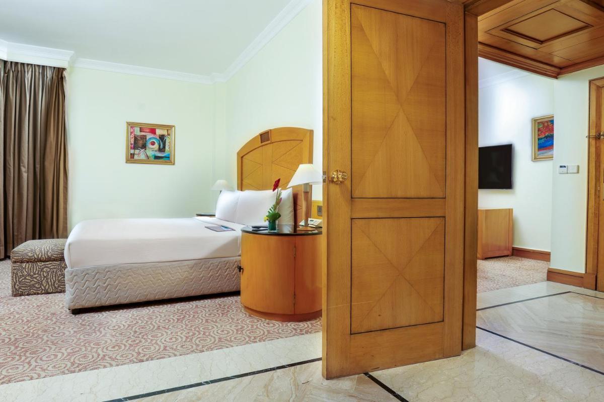 a bedroom with a bed and a wooden door at Le Royal Meridien Chennai in Chennai