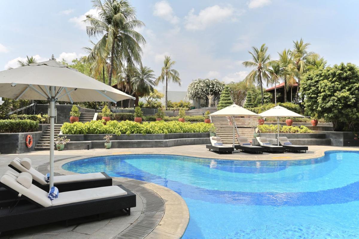 a swimming pool with lounge chairs and umbrellas at Le Royal Meridien Chennai in Chennai