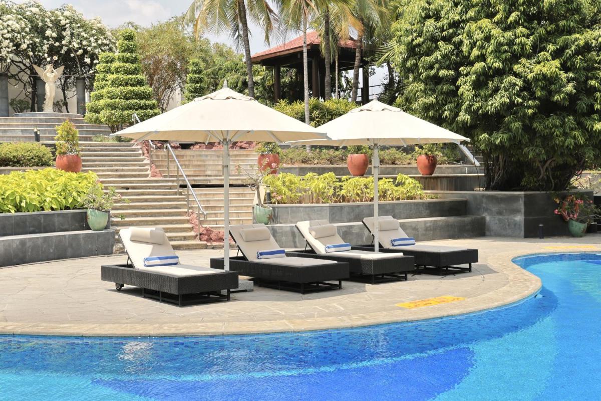 a group of chairs and umbrellas next to a pool at Le Royal Meridien Chennai in Chennai