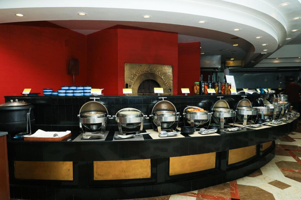 a bar with a line of silver pots and pans at Le Royal Meridien Chennai in Chennai