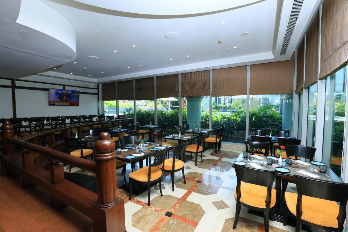 a restaurant with tables and chairs and windows at Le Royal Meridien Chennai in Chennai