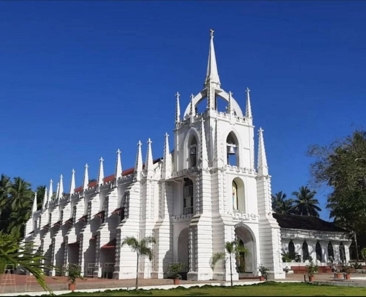 a white building with a tower on top of it at The Postcard Saligao in Calangute