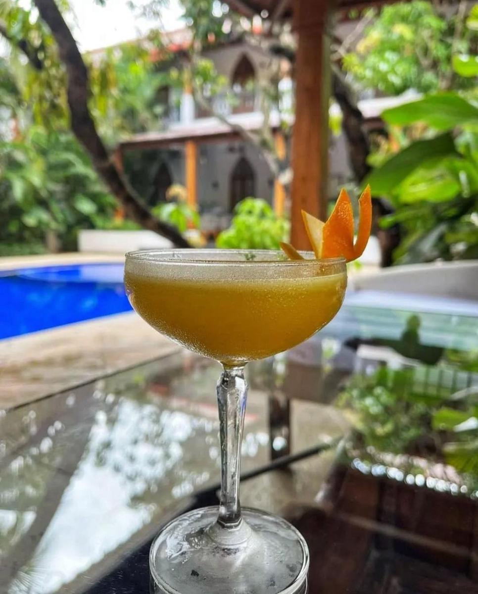 a cocktail sitting on a table with an orange garnishment at The Postcard Saligao in Calangute
