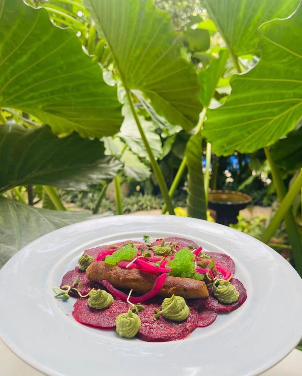 a plate of food on a table with plants at The Postcard Saligao in Calangute