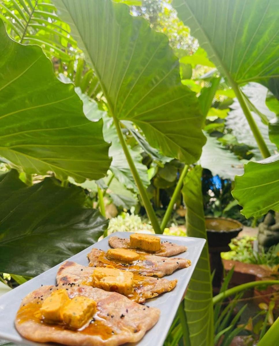 a plate of food on a table with large leaves at The Postcard Saligao in Calangute