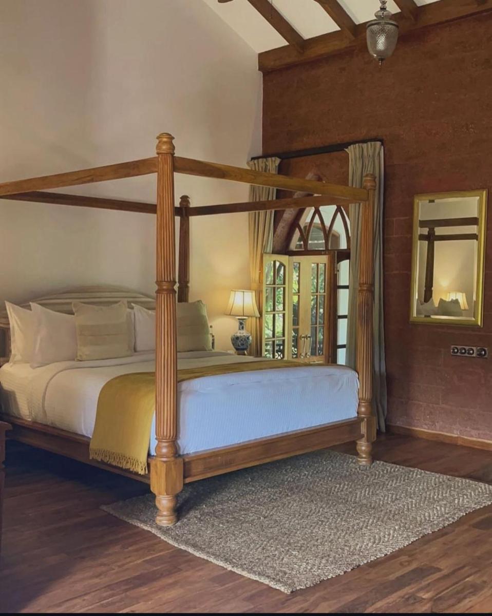 a bedroom with a canopy bed and a mirror at The Postcard Saligao in Calangute +101 photos