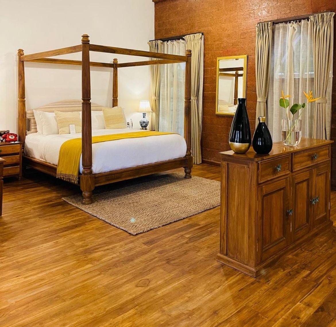 a bedroom with a canopy bed and a wooden floor at The Postcard Saligao in Calangute