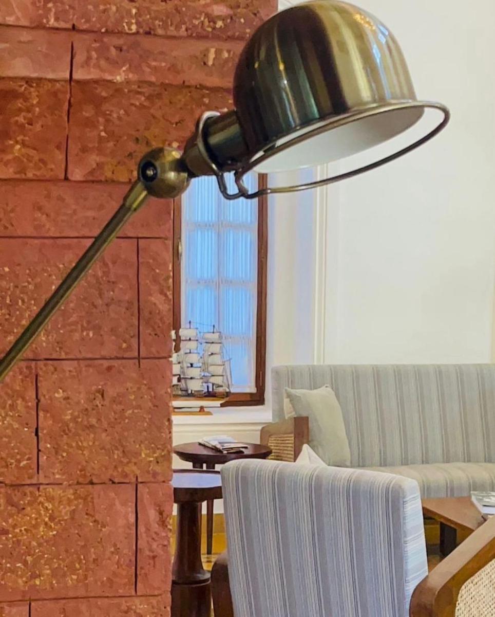 a lamp in a living room with a couch and a table at The Postcard Saligao in Calangute