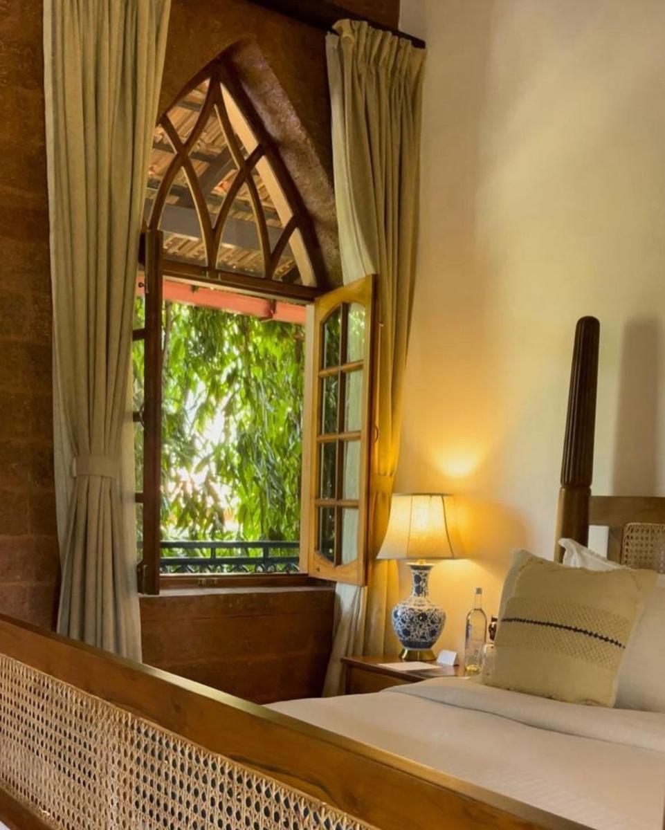 a bedroom with a bed and a window at The Postcard Saligao in Calangute