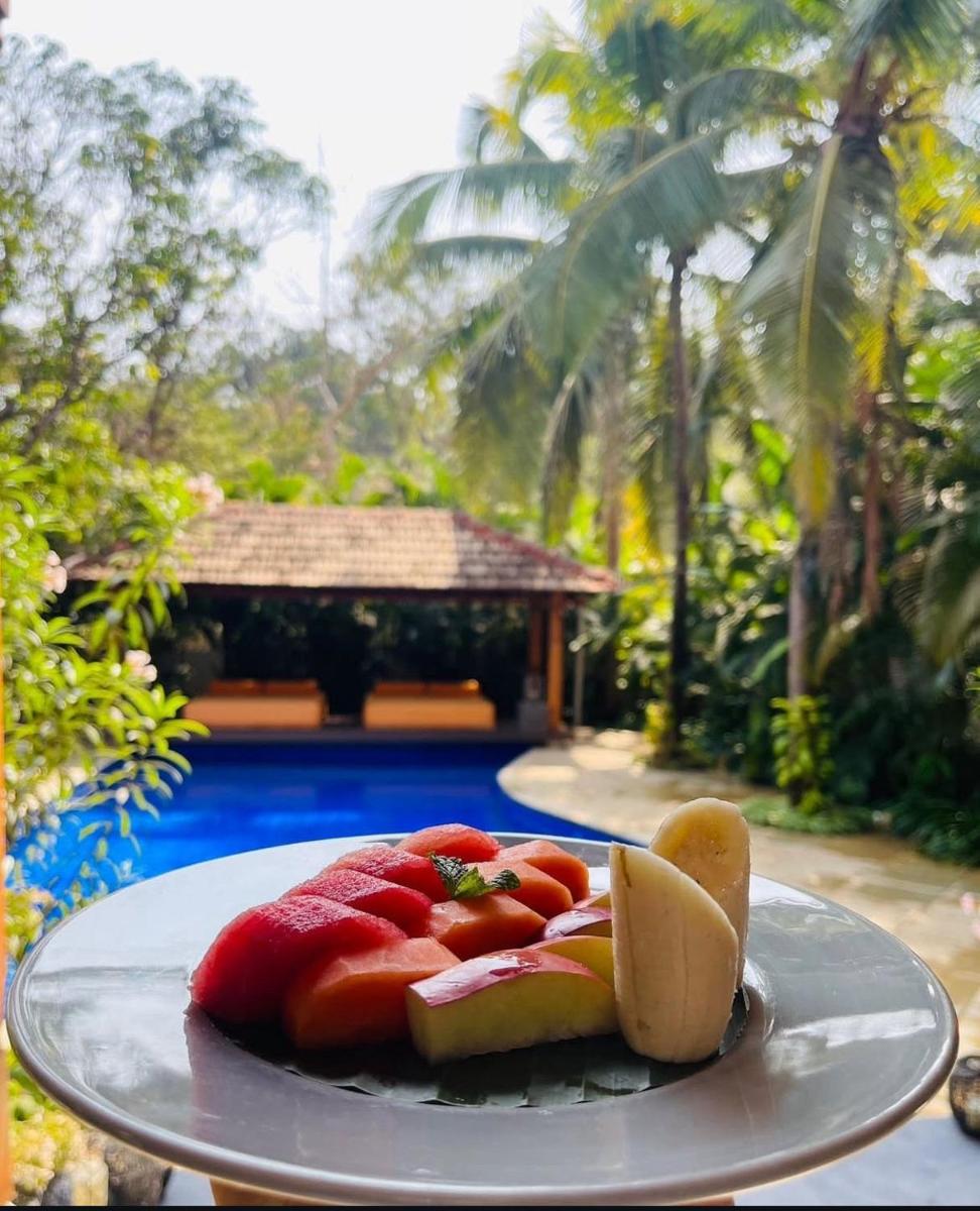 a plate of fruit on a table next to a pool at The Postcard Saligao in Calangute