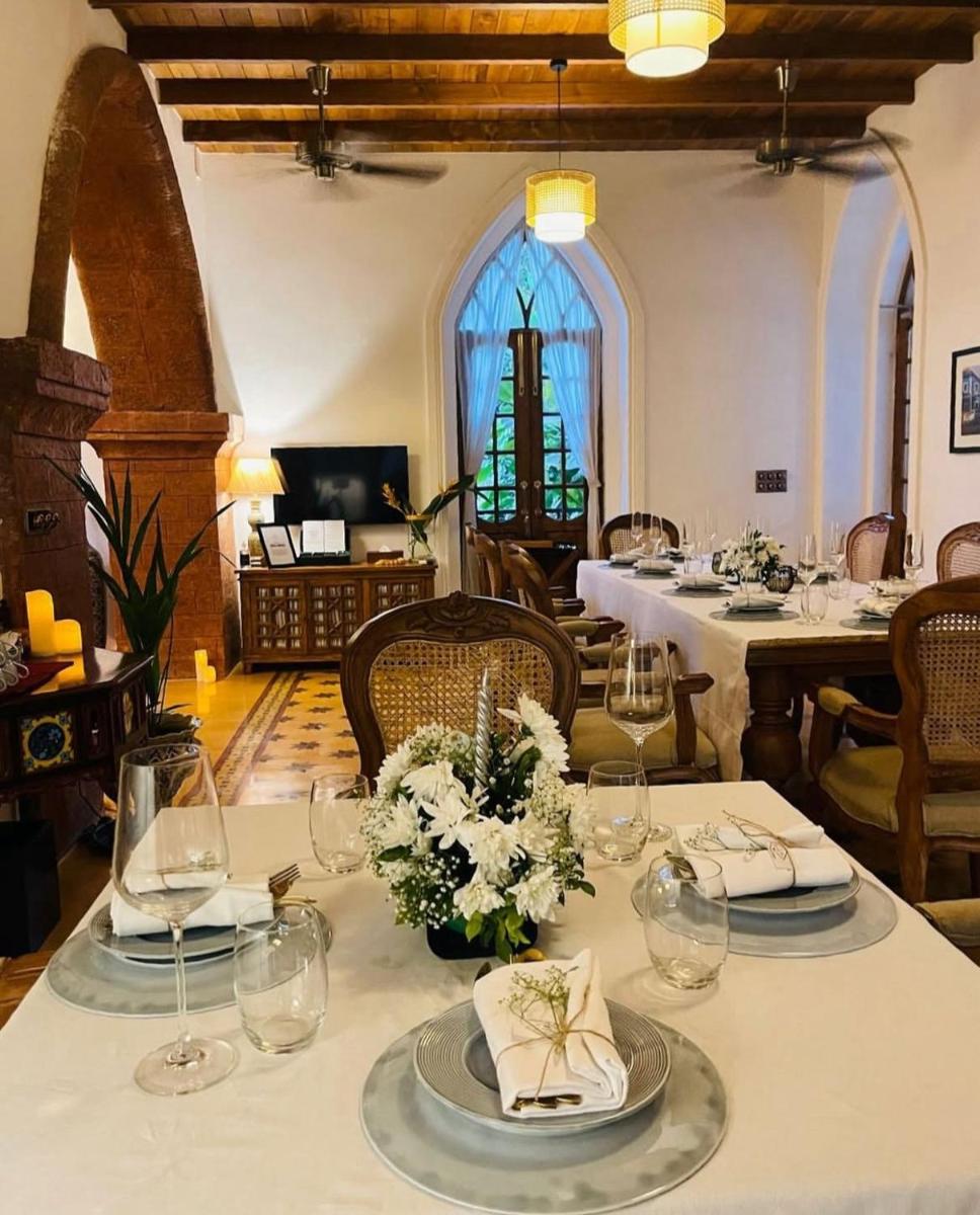 a dining room with a table with plates and glasses at The Postcard Saligao in Calangute