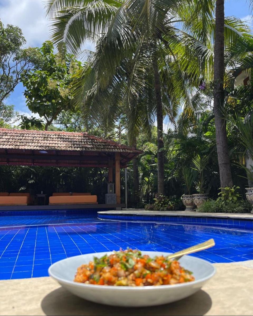 a bowl of food sitting on a table next to a pool at The Postcard Saligao in Calangute