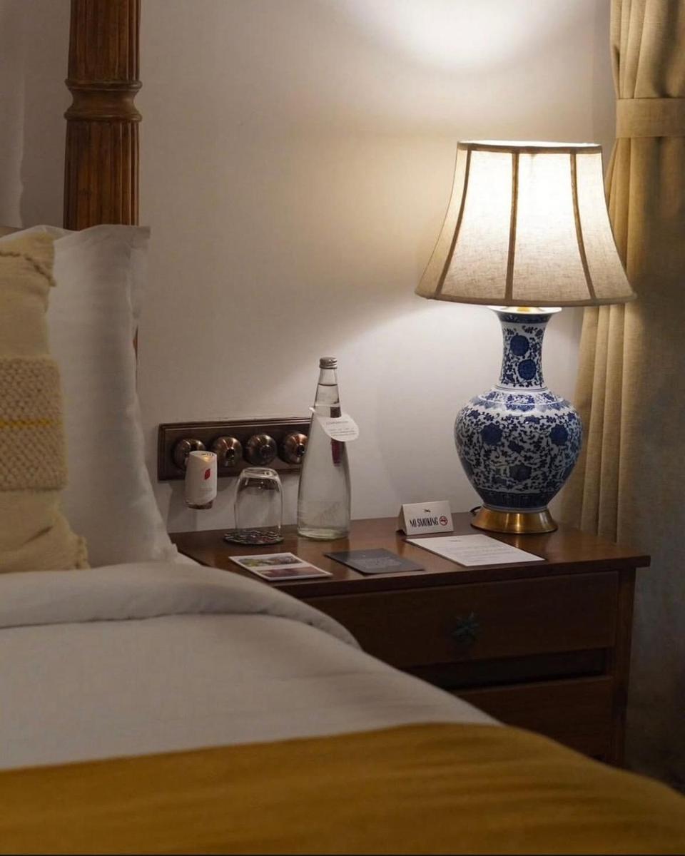 a bedroom with a bed and a lamp on a night stand at The Postcard Saligao in Calangute