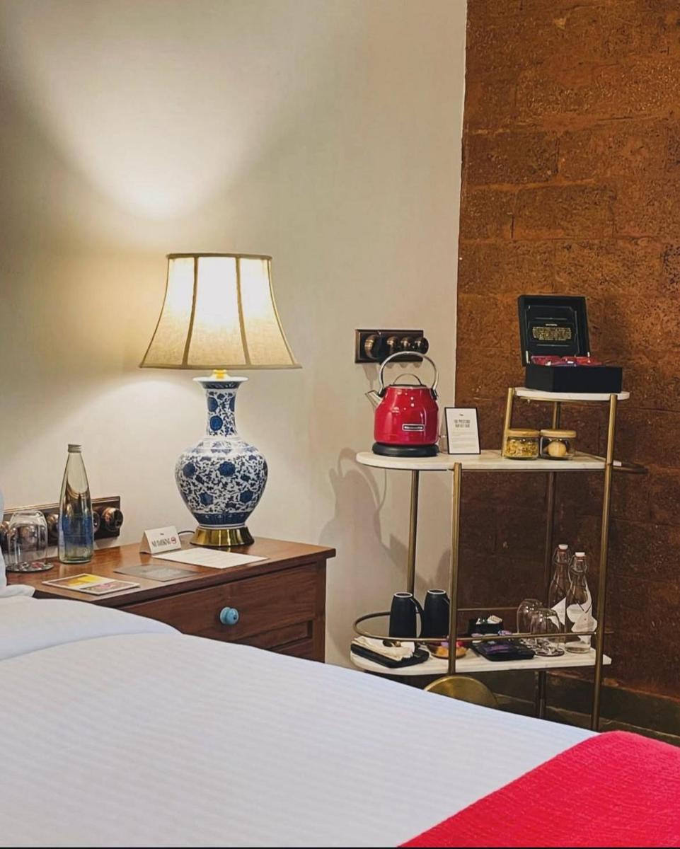 a bedroom with a bed and a lamp on a dresser at The Postcard Saligao in Calangute