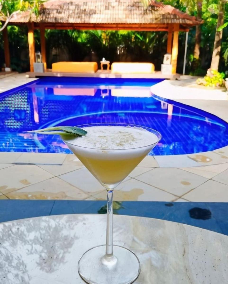 a drink sitting on a table in front of a pool at The Postcard Saligao in Calangute