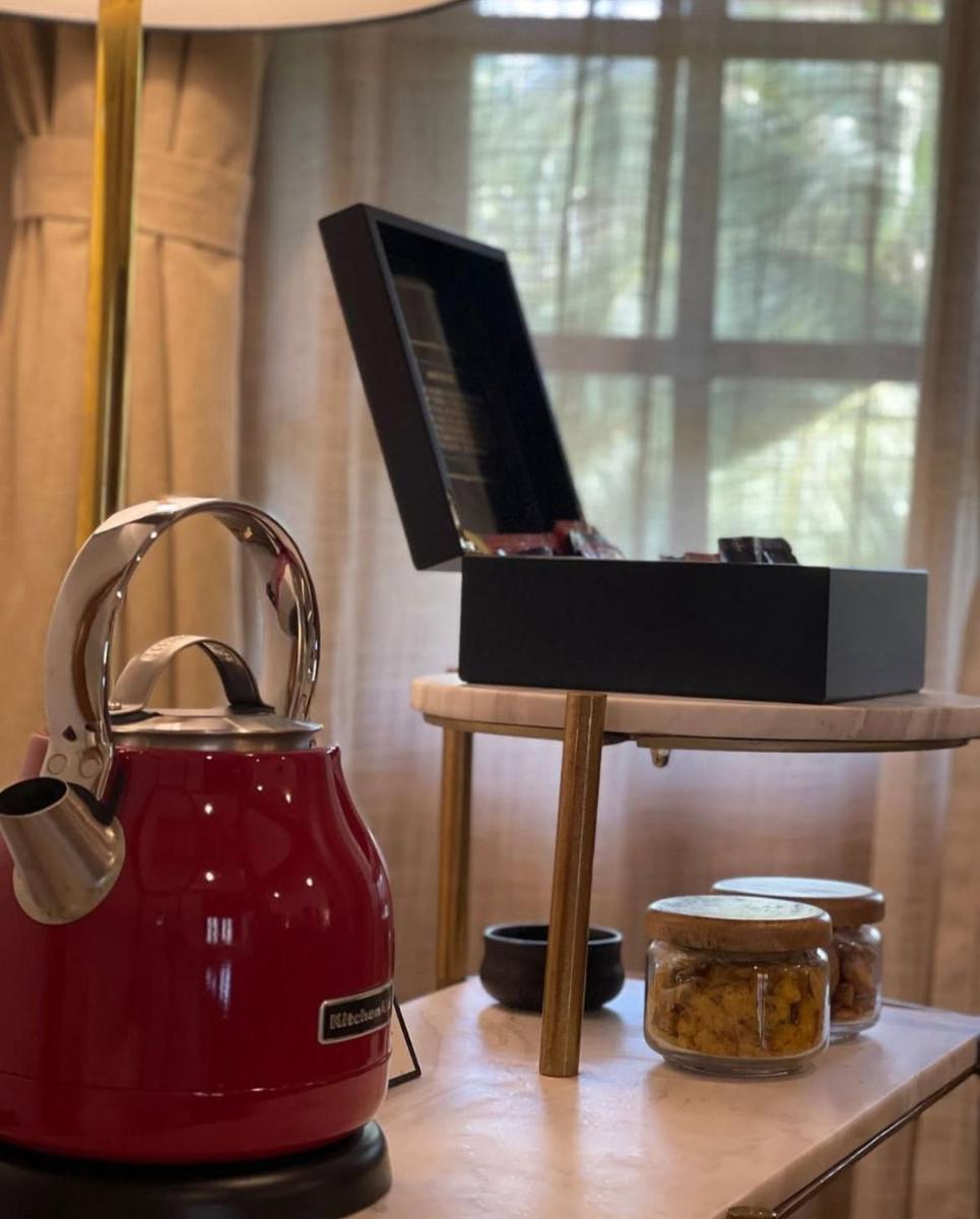 a tea pot and a laptop on a table with a tea kettle at The Postcard Saligao in Calangute