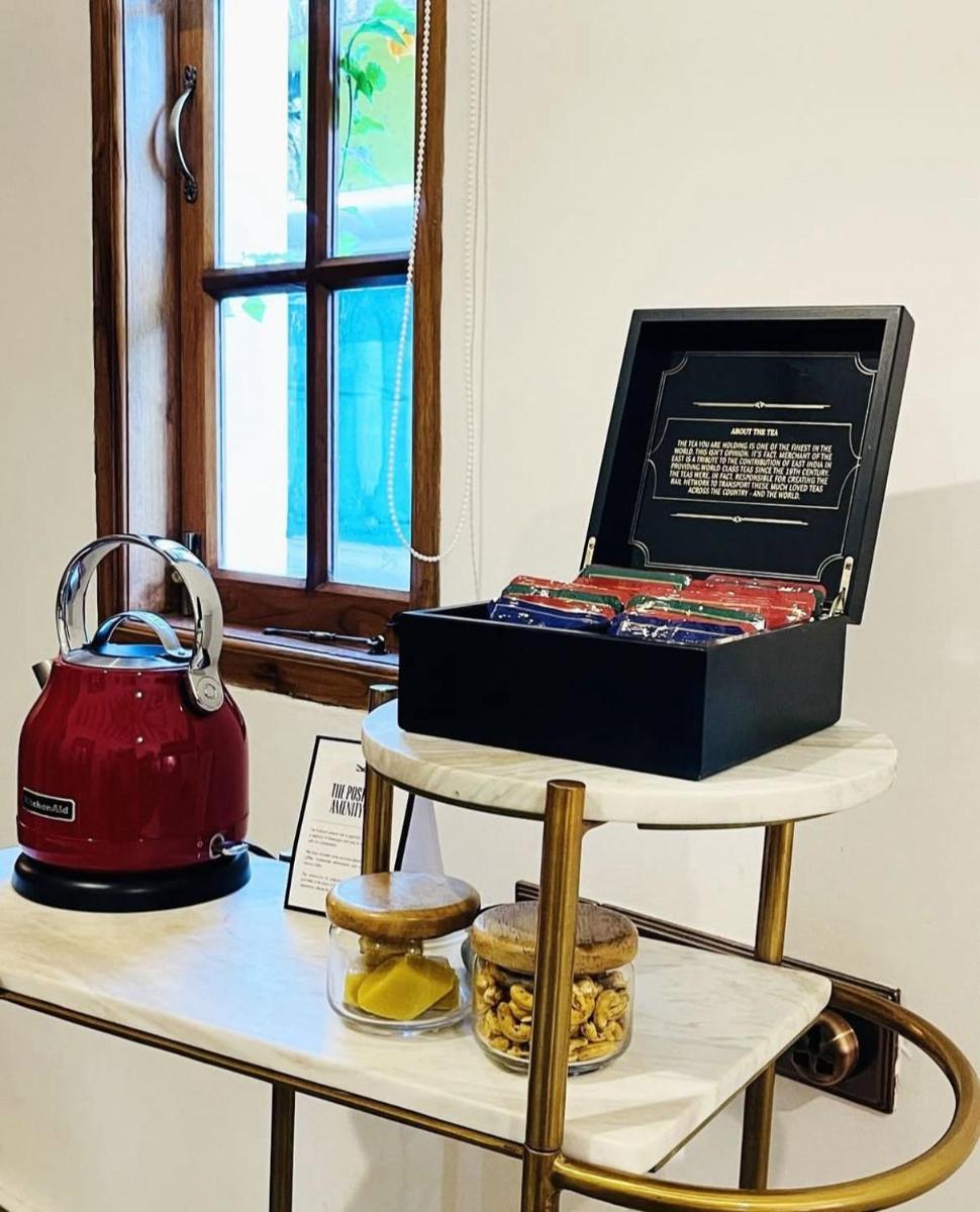a tea kettle and a box on a shelf with cookies at The Postcard Saligao in Calangute