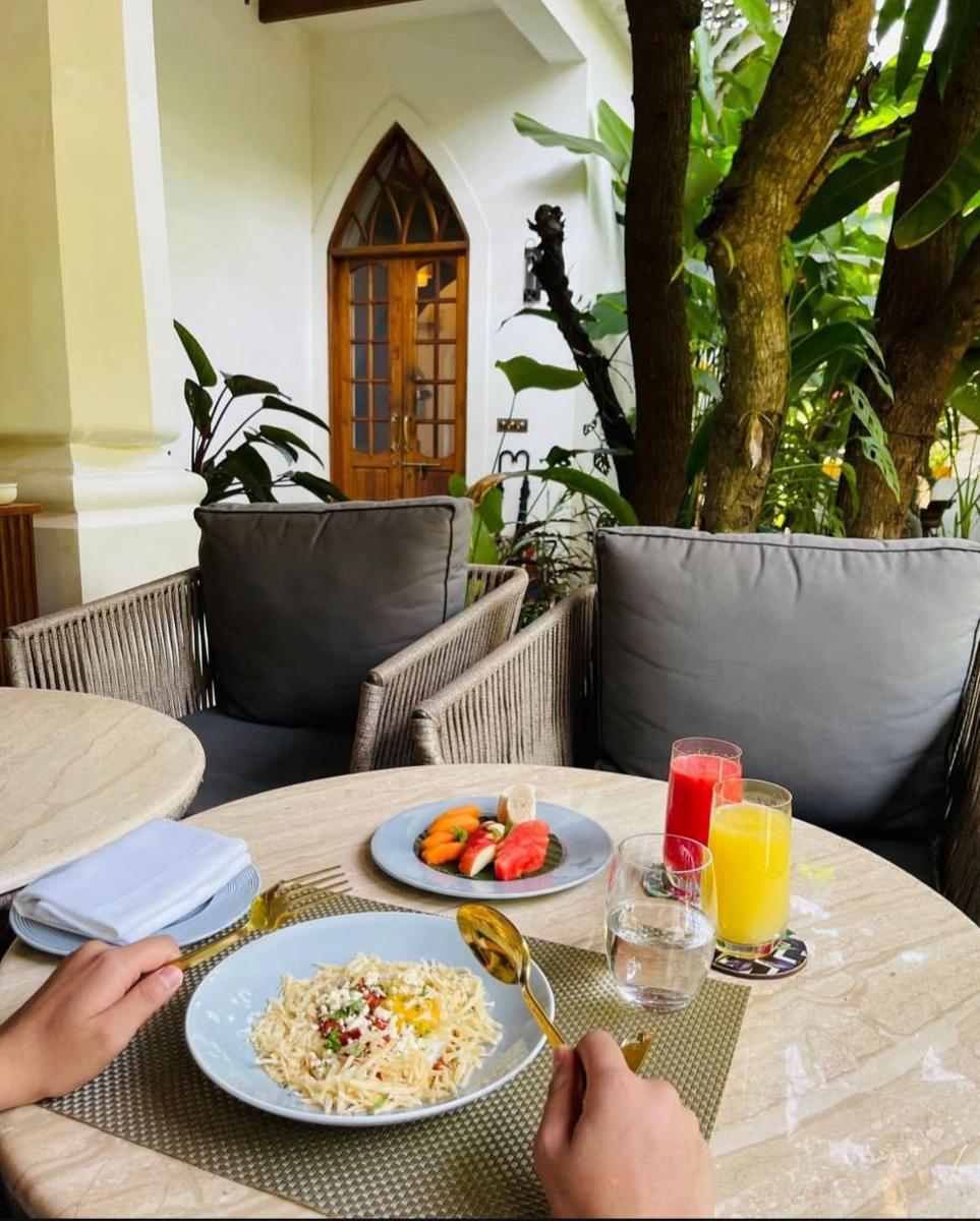 a table with two plates of food and orange juice at The Postcard Saligao in Calangute