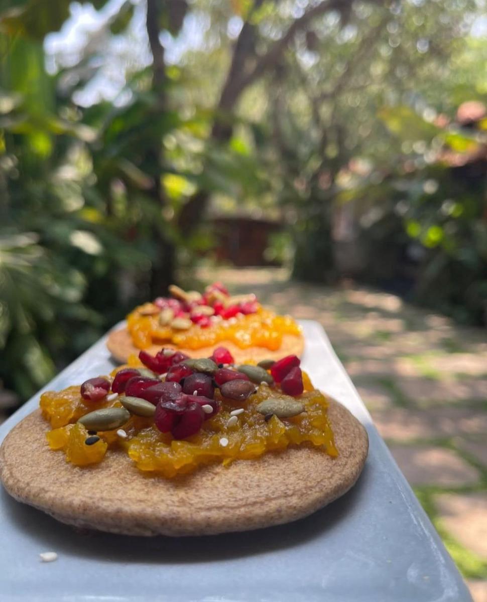 a pizza with fruit on top on a table at The Postcard Saligao in Calangute