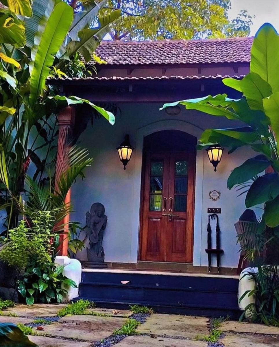 a house with a wooden door in a garden at The Postcard Saligao in Calangute