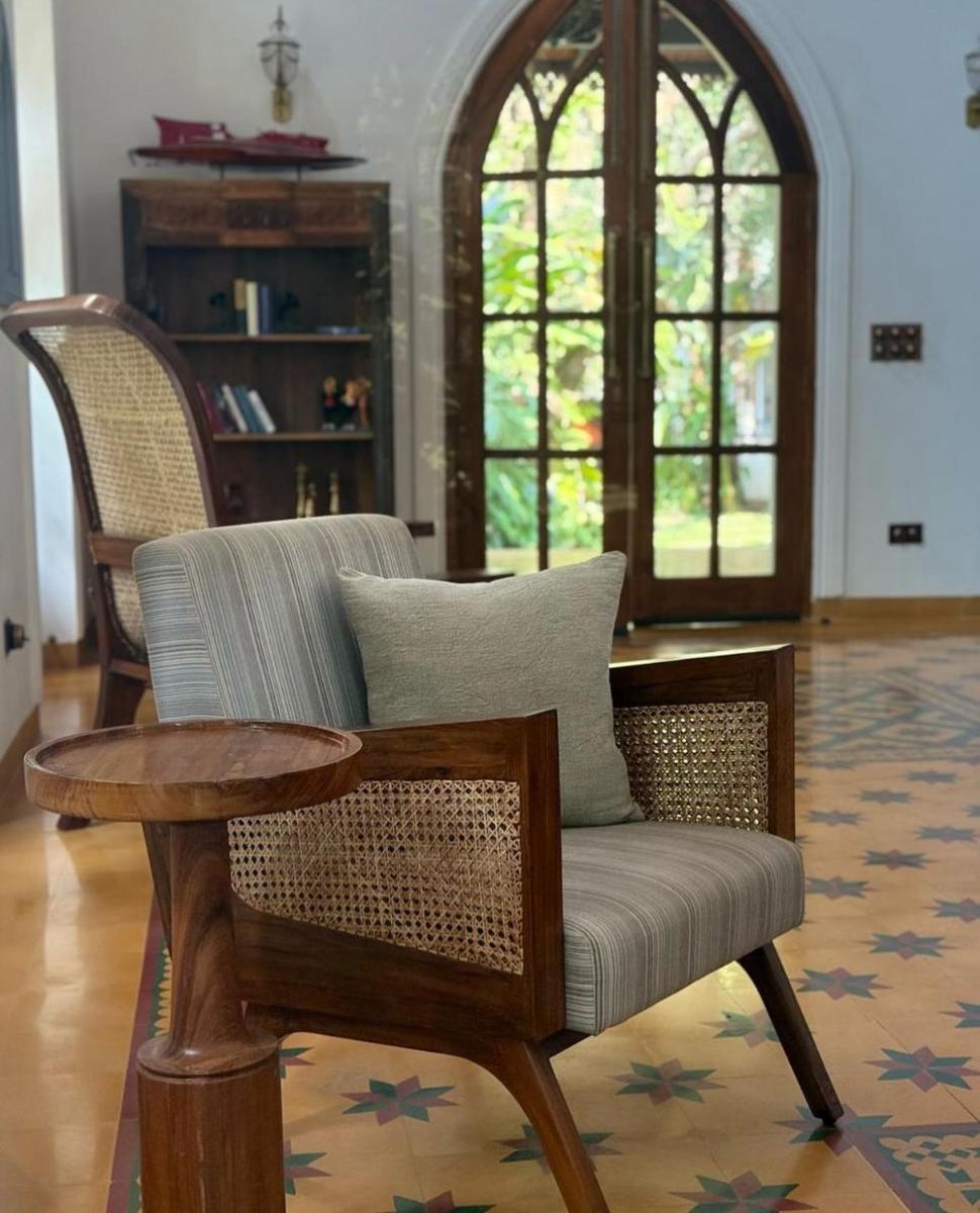 a living room with a wicker chair and a table at The Postcard Saligao in Calangute