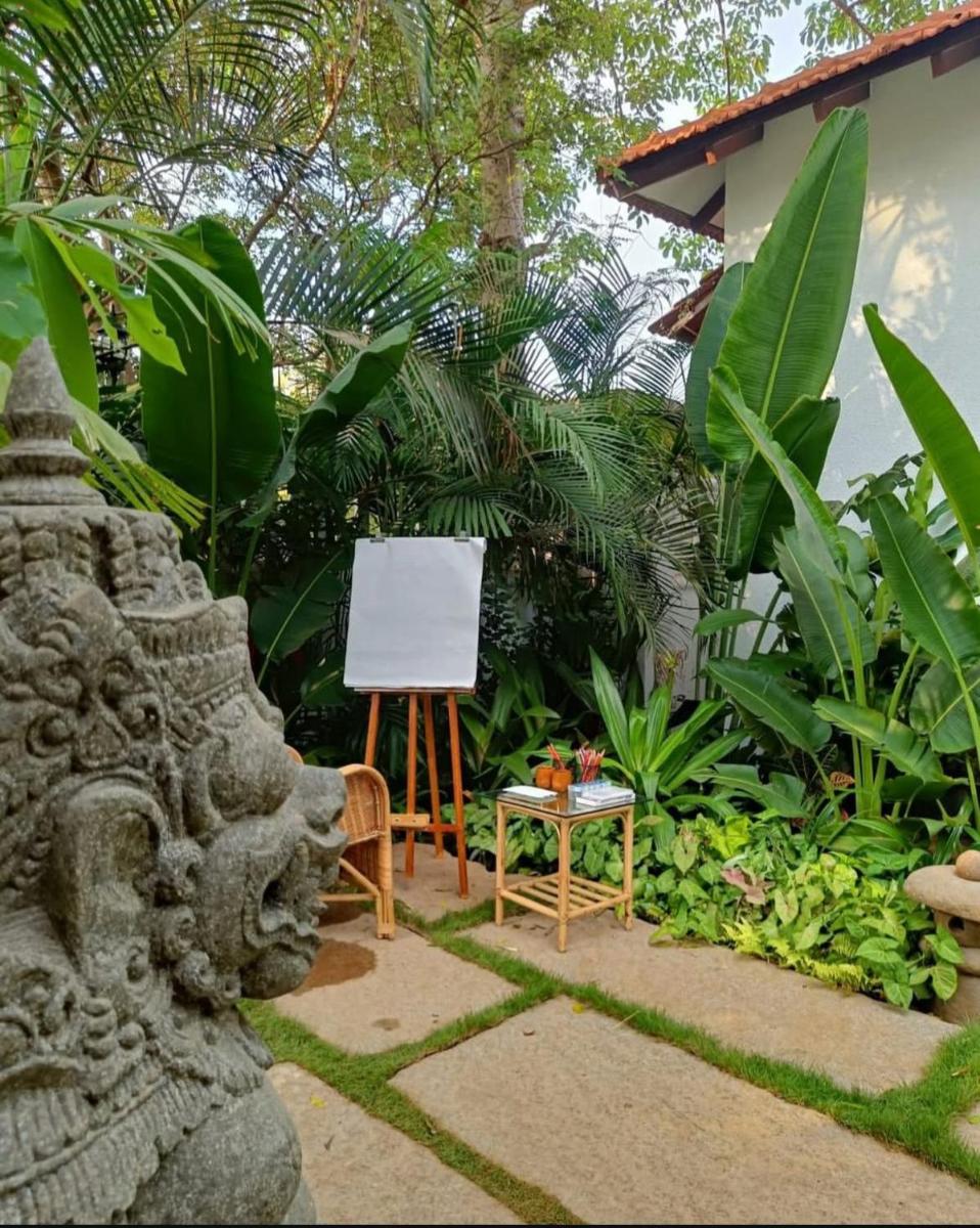 a chair and an easel in a garden at The Postcard Saligao in Calangute
